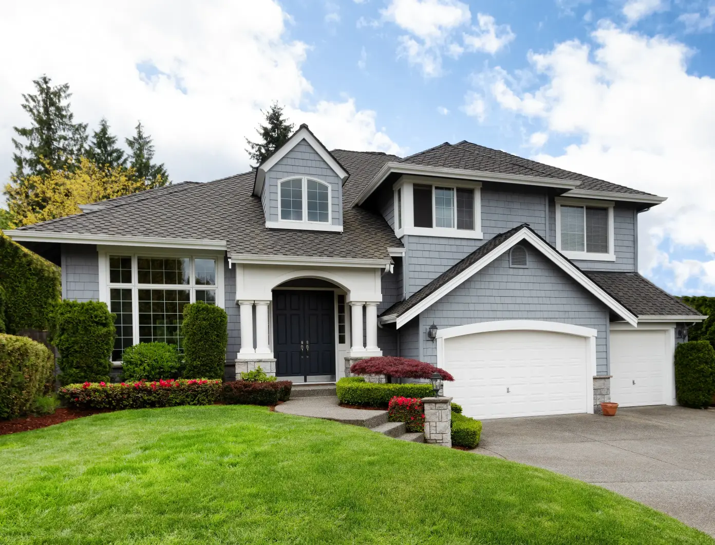 Gray house with green lawn and two garages.