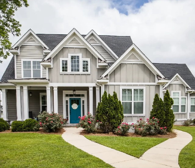 Gray house with teal door and landscaping.
