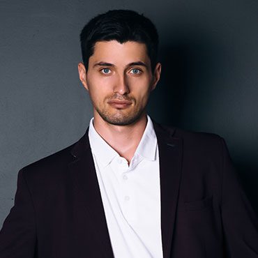 Here's an alt tag for the image: `Headshot of a man in a suit`