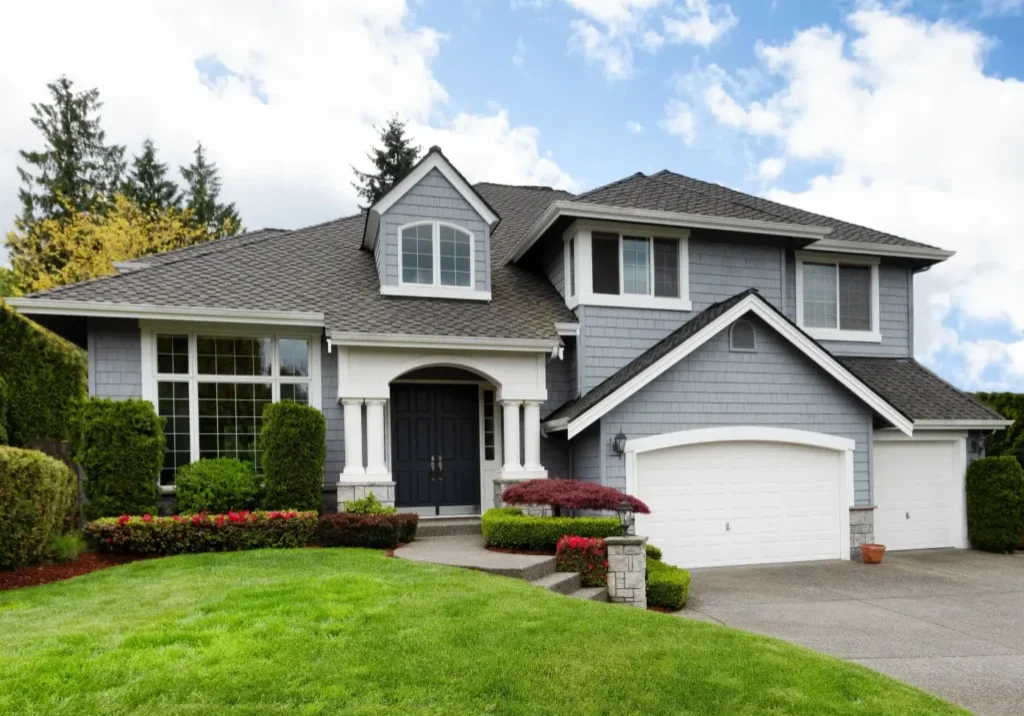 Gray house with green lawn and two garages.
